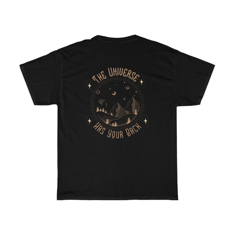 Pode incluir: T-shirt preto com um gr&aacute;fico circular nas costas. O gr&aacute;fico apresenta uma cordilheira, &aacute;rvores, estrelas e o texto "THE UNIVERSE HAS YOUR BACK" em um design circular. O design &eacute; em uma cor marrom claro.