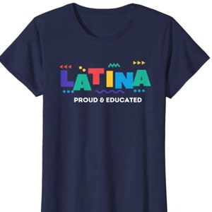 May include: Navy blue t-shirt with the word "LATINA" in colorful block letters, with decorative shapes above and below. The text "PROUD & EDUCATED" is below the word "LATINA".