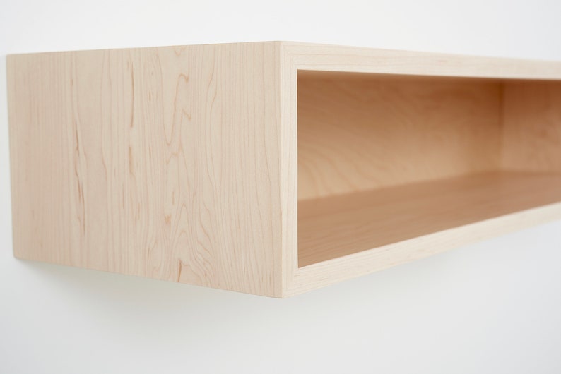 Puede incluir: Una estanter&iacute;a flotante de madera clara con un solo estante abierto. La estanter&iacute;a est&aacute; hecha de madera natural con un patr&oacute;n de veta clara.