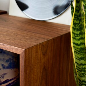 May include: Close-up of a dark brown wooden cabinet with a smooth, polished finish. The cabinet has a visible grain pattern and a sharp, defined edge.