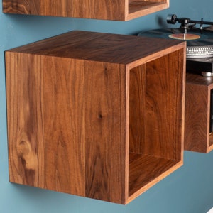 May include: A wall-mounted wooden shelf unit with a record player and stereo receiver. The shelf is made of dark wood with a natural grain pattern.