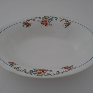 May include: White oval serving bowl with a blue rim and a floral design in shades of red, orange, yellow, and blue.