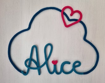 May include: A teal blue yarn cloud with the name "Alice" spelled out in the same yarn. A small red heart is in the center of the name and a larger red heart is on top of the cloud.