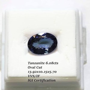 Puede incluir: Una piedra preciosa de Tanzanite de 6,08 quilates de corte ovalado en una caja de presentación blanca. La piedra preciosa es de color azul-violeta oscuro. La caja tiene el texto "Tanzanite 6.08cts Oval Cut 13.92x10.15x5.70 VVS/IF IGI Certification".