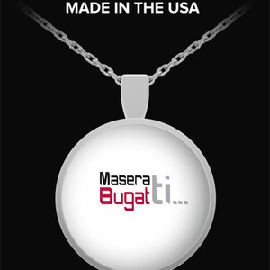 Op de afbeelding: Een zilverkleurige hangerketting met een ronde, witte hanger. De hanger toont de woorden "Maserati Bugatti" in zwarte, rode en grijze letters. De ketting is zilverkleurig en de tekst "MADE IN THE USA" staat bovenaan.
