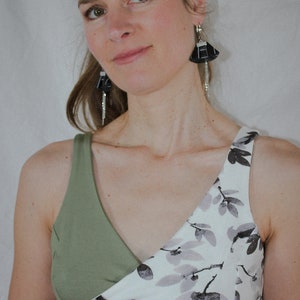 May include: A green and white floral print sports bra with black lace trim. The bra has a criss-cross design in the front.