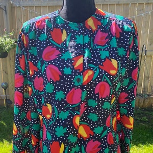 May include: A long-sleeved button-up shirt with a black background and a colorful floral print. The print features red, pink, yellow, and green tulips on a black background with white polka dots.