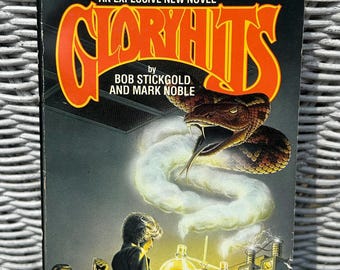 May include: Vintage paperback book cover for "Gloryhits" by Bob Stickgold and Mark Noble. The cover features a snake with its tongue out, a lab scene, and the title in orange. The text reads "An Explosive New Novel".