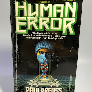 May include: A paperback book cover with a black background and green text that reads "HUMAN ERROR". The cover features a person wearing a blue surgical cap and a blue face mask, with a DNA strand in front of them. The text "The Frankenstein theme is audacious and unexpected... a fine novel on any account." - The Washington Post is printed below the title.
