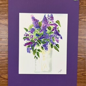 Peut inclure: Une peinture à l'aquarelle d'un bouquet de fleurs de lilas pourpres dans un pot en verre transparent. Les fleurs sont disposées dans un style lâche et naturel, et le pot est simple et élégant. La peinture est signée "Stickler" en bas à droite.