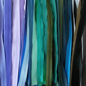 May include: A variety of zipper tapes in different colors, including blue, purple, green, and black. The tapes are arranged vertically and are all the same length.