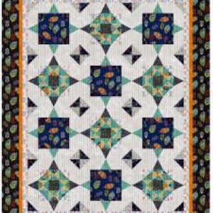 Op de afbeelding: Een quilt met een witte achtergrond en een herhalend patroon van blauwe, groene en oranje vierkanten met een stervormig ontwerp. De quilt is omgeven door een zwarte en oranje rand.