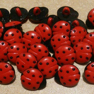 May include: A collection of red and black ladybug buttons. The buttons are made of plastic and have a shiny finish. They are approximately 2.5 cm in diameter.