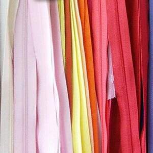 May include: Assortment of colorful zipper tapes in various shades of pink, yellow, orange, red, and blue.