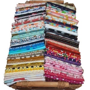 May include: A large collection of folded fabric pieces arranged in two vertical stacks within a woven basket. The textiles feature a wide variety of colours, including pink, yellow, blue, red, and black, with diverse patterns like florals, geometric shapes, and animal prints.