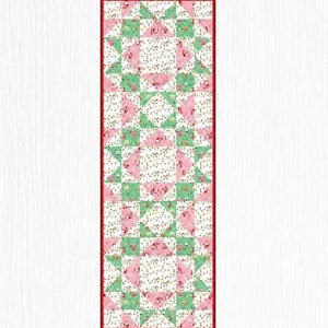 May include: A rectangular quilt with a repeating pattern of pink and green triangles and squares, framed by a red border. The quilt features floral and dotted patterns within the geometric shapes, set against a white background.