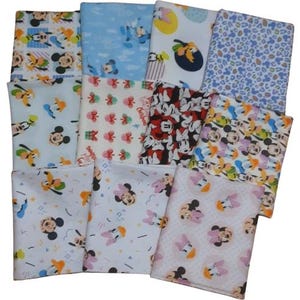 Peut inclure: Un assortiment de carrés de tissu pliés avec des imprimés de personnages de dessins animés. Les tissus présentent Mickey Mouse, Minnie Mouse, Donald Duck et d'autres personnages dans des motifs colorés. Les tissus sont dans des tons de bleu, blanc, rouge et jaune.