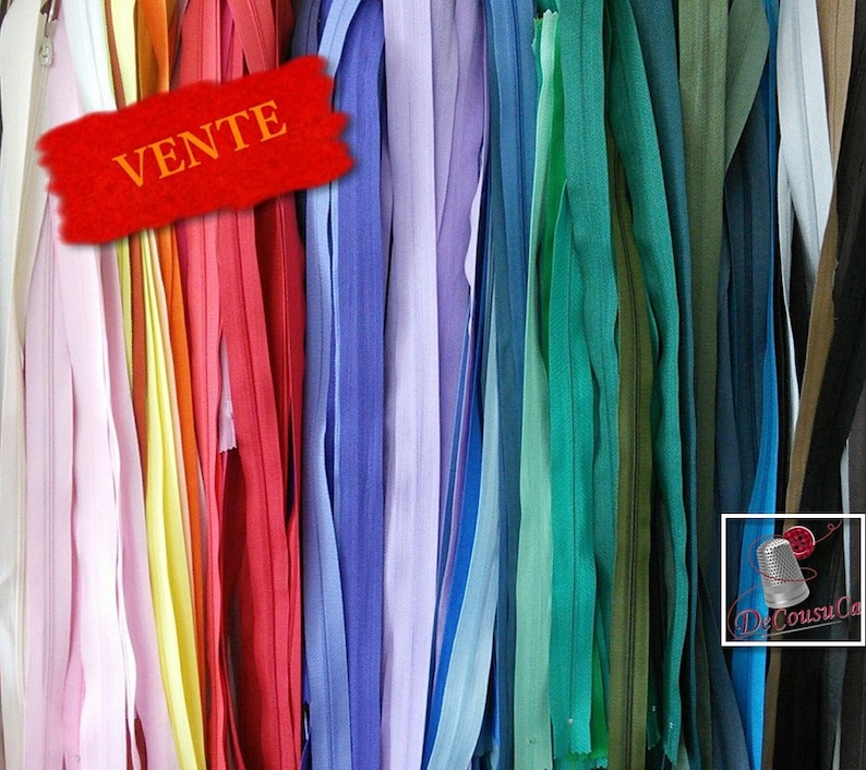 May include: A variety of colorful zipper tapes in different lengths and colors, including pink, yellow, red, blue, green, and brown. The word "VENTE" is written in red on a white background.