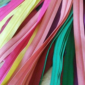 May include: A collection of colorful zipper tapes in various shades of pink, yellow, green, and purple. The zipper tapes are arranged in a fan shape, showcasing the different colors and textures.
