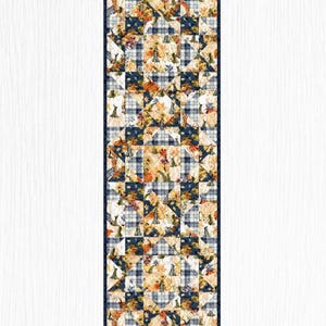 May include: A rectangular table runner featuring a patchwork design of autumn-themed fabric. The pattern alternates between squares of navy blue and white plaid and squares displaying orange pumpkins, gourds, and fall leaves on a cream background.