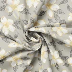 Peut inclure: Tissu avec un motif floral répété. De grandes fleurs blanches avec des centres et des contours jaunes sont dispersées sur un fond gris clair. Des feuilles grises à imprimé léopard sont également présentes.