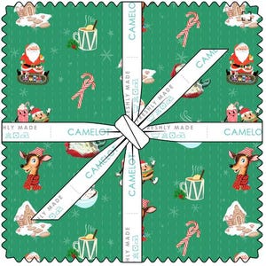 Peut inclure: Une pile de carrés de tissu aux bords dentelés, présentant un fond vert avec un motif de Noël composé de Père Noël, rennes, sucres d'orge et tasses. Un ruban blanc imprimé du texte CAMELOT FRESHLY MADE entoure la pile de tissu.