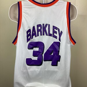 May include: White mesh basketball jersey with the name "BARKLEY" and the number "34" in purple. The jersey has orange and purple trim around the collar and arm openings.
