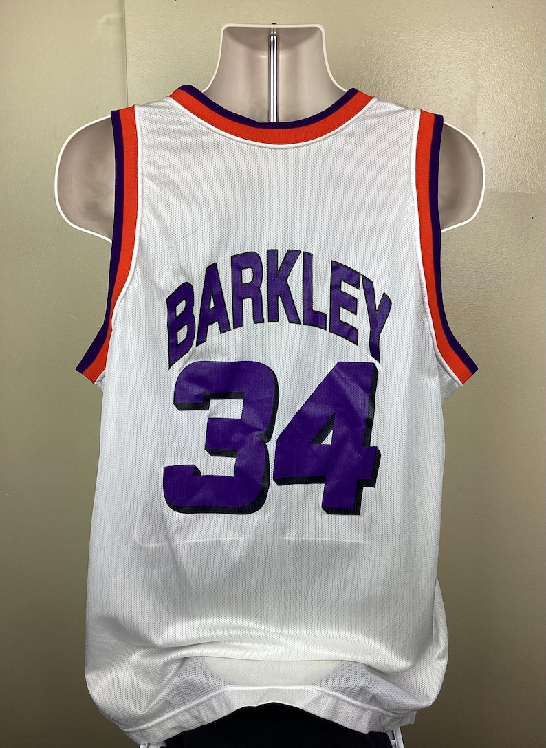 May include: White mesh basketball jersey with the name "BARKLEY" and the number "34" in purple. The jersey has orange and purple trim around the collar and arm openings.