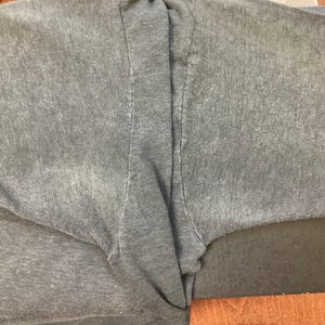May include: A gray t-shirt with a faded look. The shirt is folded in half and the fabric is textured.