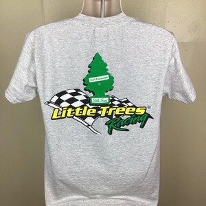 May include: A gray t-shirt with a green pine tree graphic and the text "Little Trees Racing" in yellow and black. The pine tree graphic has a white rectangle with the text "Car Freshener" on it.