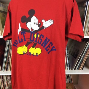 K&ouml;nnte beinhalten: Rotes T-Shirt mit einem Cartoon-Bild von Mickey Mouse und dem Text "Walt Disney World" in Blau.