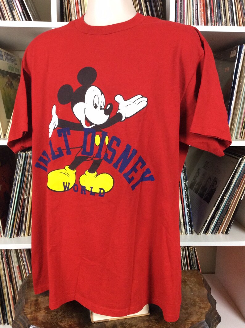 K&ouml;nnte beinhalten: Rotes T-Shirt mit einem Cartoon-Bild von Mickey Mouse und dem Text "Walt Disney World" in Blau.