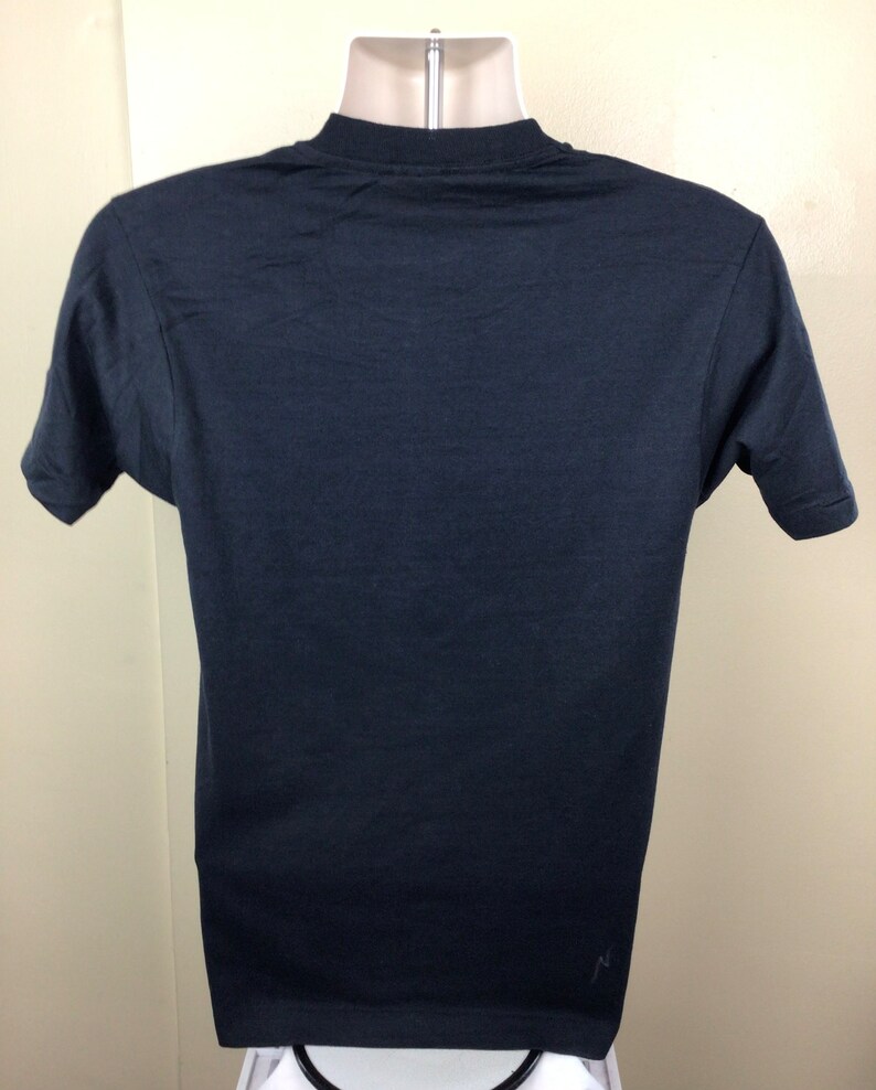 Pu&ograve; includere: Una maglietta nera a maniche corte con un piccolo logo bianco in basso a destra.