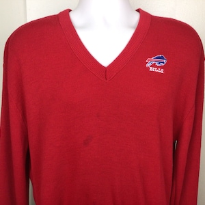 May include: Red V-neck sweater with the Buffalo Bills logo embroidered on the chest. The logo is blue, white, and red.