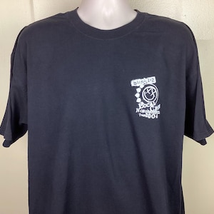 May include: Black t-shirt with a white graphic of the band Blink-182's logo and the text "Local  Outlaw  North American Tour 2004".