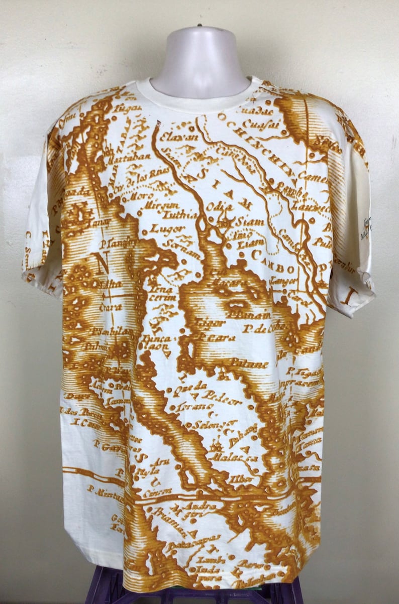 May include: White t-shirt with a brown vintage map print of Southeast Asia. The map includes the text "SIAM", "CAMBO", "OCHINCHIY", "Luthia", "Odil Siam", "Sornam", "Liam", "Plan Langy", "Mirim", "Lena Cerim", "Dinca", "P. de Patane", "Lorane", "Selen", "Malacca", "Andra", "11bo", "Praman", "Toda", and "C. Sem".