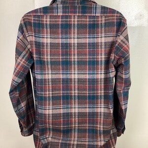 May include: A long-sleeved plaid shirt in brown, green, and beige tones. The shirt has a button-down collar and a relaxed fit.