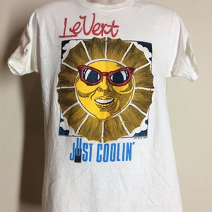 May include: White t-shirt with a cartoon sun wearing red sunglasses and the text "LeVert Just Coolin'" printed on the front.