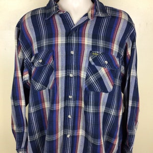 May include: A blue, red and white plaid long-sleeved button-down shirt with two chest pockets. The shirt has the brand name "Duck Head" on the right pocket.