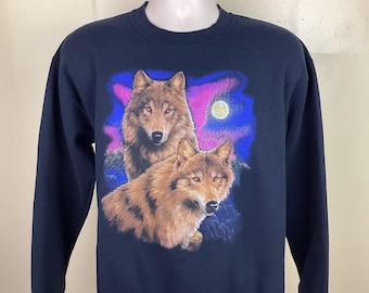 May include: A navy blue sweatshirt featuring a graphic print of two wolves howling at the moon. The wolves are surrounded by a pink and blue sky.