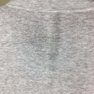 May include: Close-up of a gray collared shirt. The shirt is made of a soft, textured fabric. The collar is a lighter shade of gray than the body of the shirt.