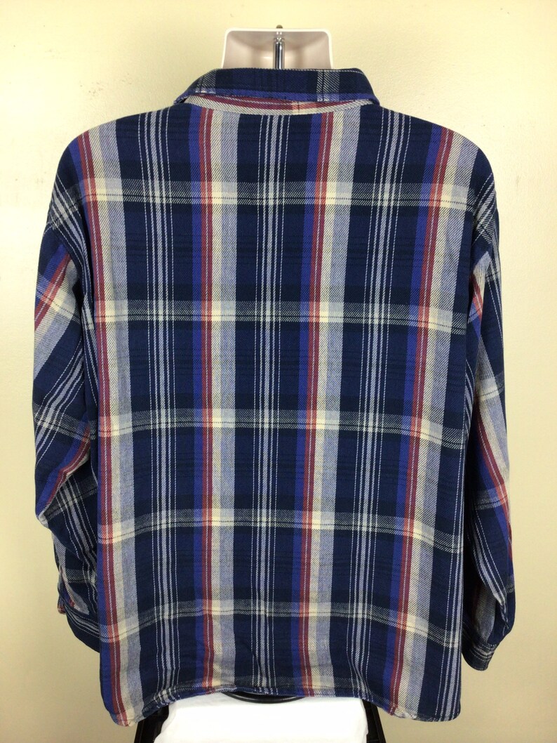 May include: A blue, red and white plaid long-sleeved shirt. The shirt has a button-down collar and a relaxed fit.