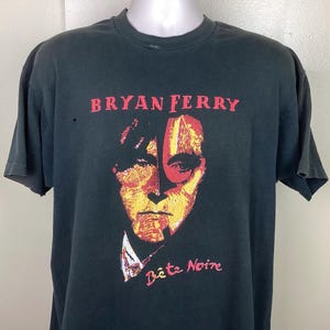 May include: Black t-shirt with a red, yellow, and orange illustration of Bryan Ferry's face. The text "Bryan Ferry" and "Bête Noire" are printed on the shirt.