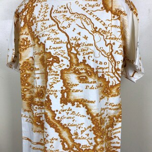 May include: White t-shirt with a vintage-style map print in brown. The map features various locations and names, including Siam, Odia, and Cambo.
