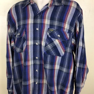 May include: A blue, red and white plaid long-sleeved button-down shirt with a single chest pocket and the text "GearWear" on the pocket.