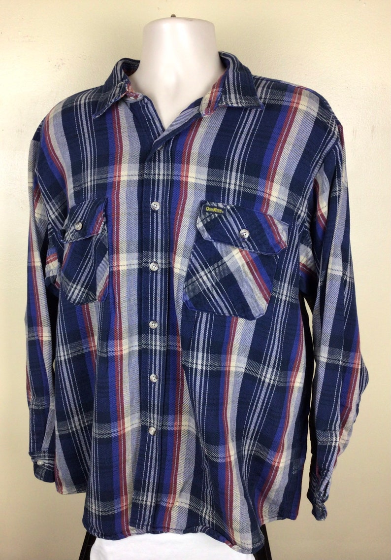May include: A blue, red and white plaid long-sleeved button-down shirt with a single chest pocket and the text "GearWear" on the pocket.
