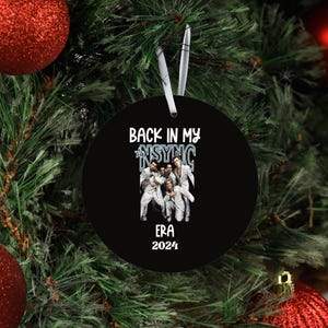 May include: Black and white round Christmas ornament with the text "Back in My *NSYNC Era 2024" and a photo of the band *NSYNC.