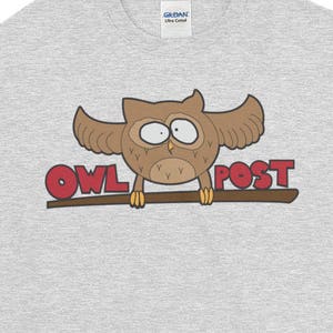 May include: Gray short-sleeved t-shirt with a cartoon owl perched on a branch. The owl is brown with red eyes and the text "OWL POST" is written in red letters.