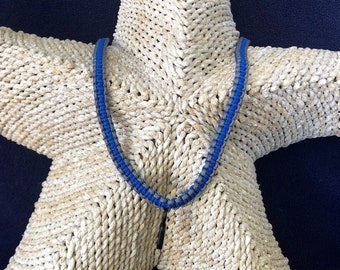May include: A blue and gray beaded necklace on a white starfish background.