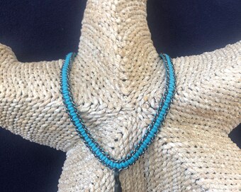 May include: A turquoise and black paracord necklace with a black metal clasp.